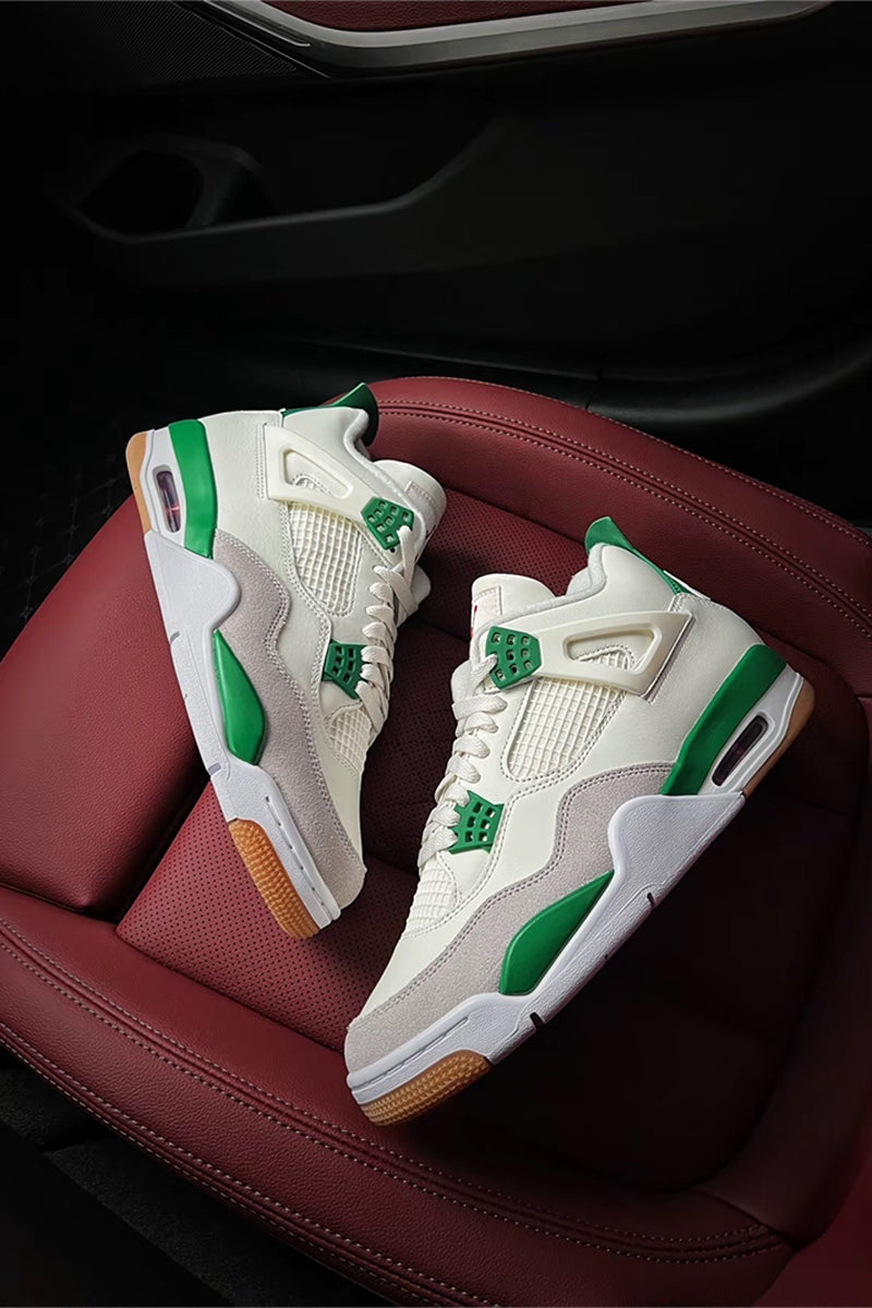 A pair of white and green Air Jordan 4 Retro sneakers displayed on a dark red leather car seat.