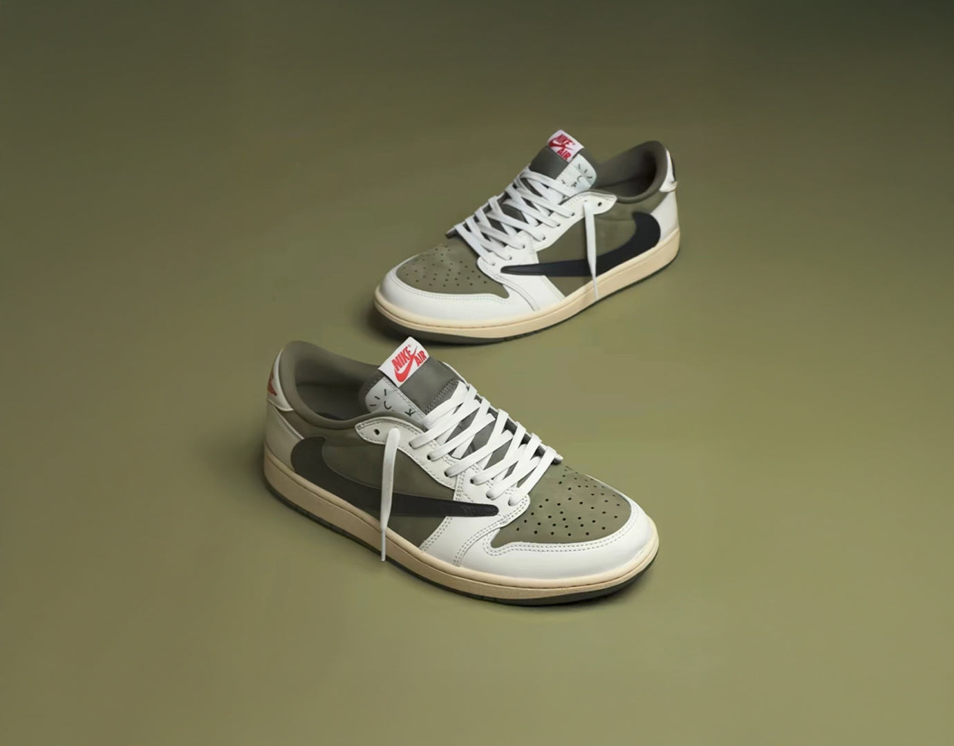 A pair of low-top sneakers displayed on a solid olive green background. The shoes feature white leather overlays, textured gray suede panels, a dark gray side stripe, a beige midsole, and a small red and white tongue label.